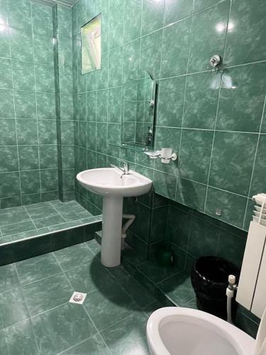 a green tiled bathroom with a sink and a toilet at Family Guest House in Bakuriani