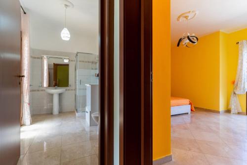 uma casa de banho com paredes amarelas, um WC e um lavatório. em Casa Bellaria by BarbarHouse em Copertino