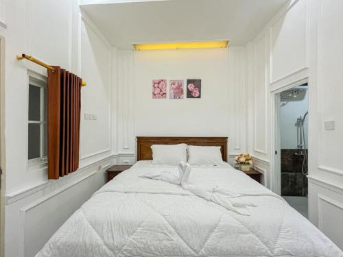 a white bedroom with a large bed with white sheets at Sakura Guest House by The Lavana in Batu