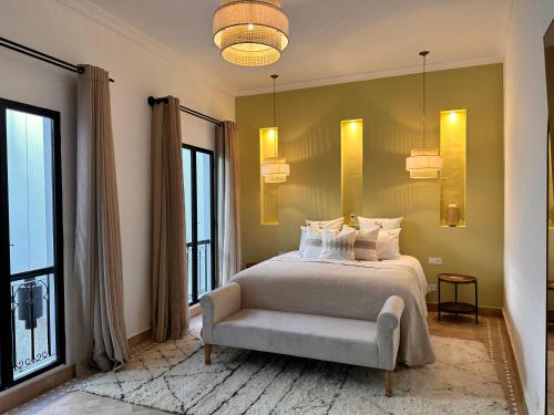 a bedroom with a bed and a chair and windows at Riad Belharra in Marrakech