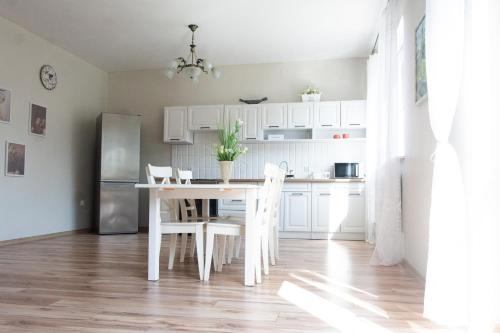 a kitchen with white cabinets and a table and chairs at Babie Lato in Mrągowo