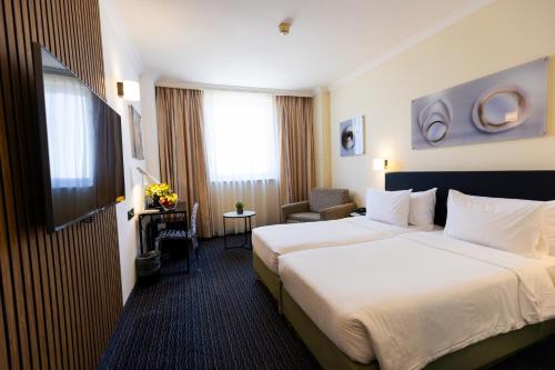 a hotel room with a large bed and a chair at Grand Beach Hotel in Tel Aviv