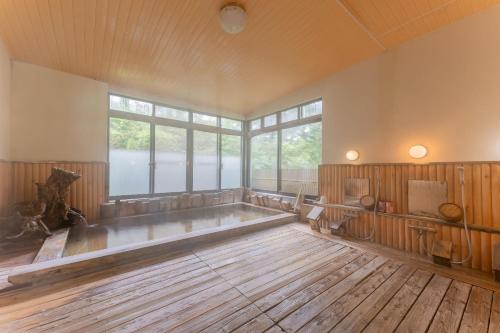 an empty room with a large window and a wooden floor at 檜湯の宿　松伯 in Aoki-gemi