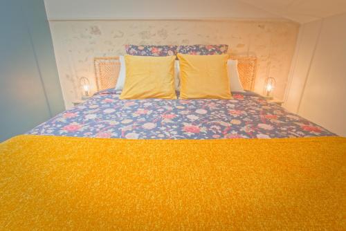 a bed with two yellow pillows on top of it at La Belle lurette in Bressuire