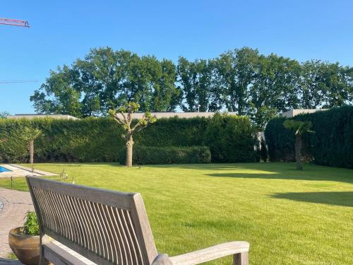 a wooden bench sitting in a park with a green lawn at B&B 1001 nacht in Zonhoven