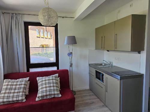 BarsbekにあるFerienwohnung zwischen Laboe und Schönbergの赤いソファとキッチンのあるリビングルーム