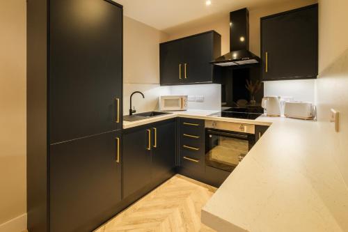 a kitchen with black cabinets and white counter tops at West End Retreat - SJA Stays - 2 Bed Apartment in Aberdeen