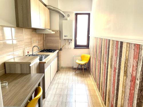 a kitchen with a counter and a yellow chair in it at Summerland Vibe Apartments in Mamaia Sat/Năvodari