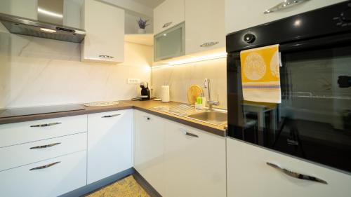a kitchen with white cabinets and a black appliance at Gogo in Delnice