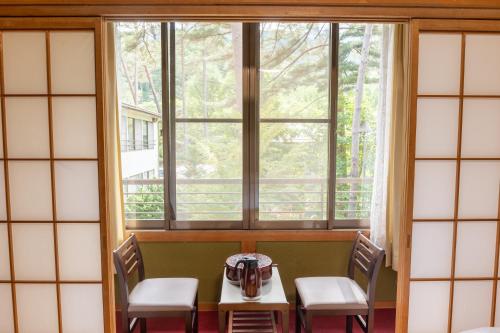a table and chairs in a room with a window at 檜湯の宿　松伯 in Aoki-gemi