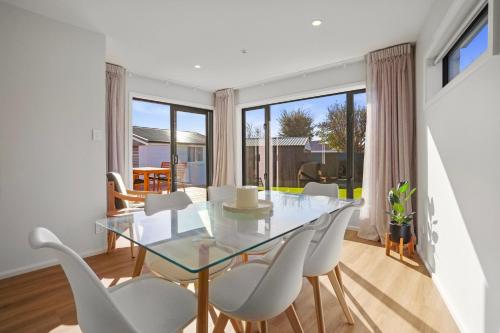 a dining room with a glass table and white chairs at Private Family 4BR Home, Near Airport, Free Parking in Christchurch