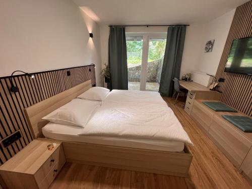 - une chambre avec un grand lit blanc et une fenêtre dans l'établissement Prenočišča Mraz, à Velenje