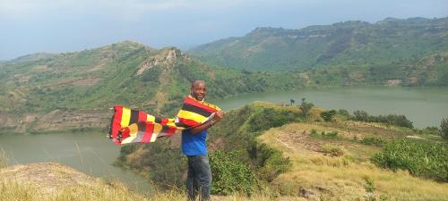 a man standing on a hill holding a kite at Muga Eco Village in Ntungamo
