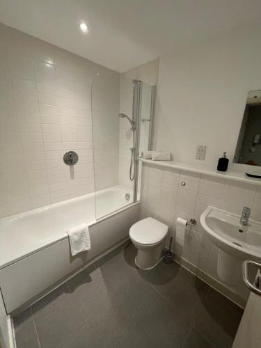 a bathroom with a toilet and a tub and a sink at 2 Bedroom Flat in Bedford