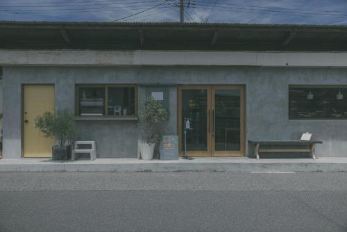 a building with two plants and a bench on the sidewalk at Nari Nuttari Nari in Niigata