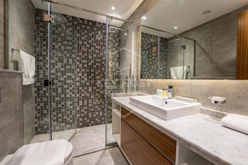 a bathroom with a sink and a glass shower at KeyHost - Large 1BR Apartment near Five Hotel JVC - Dubai - K310 in Dubai