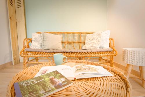una sala de estar con un banco de mimbre y una mesa con un libro en La Belle lurette, en Bressuire