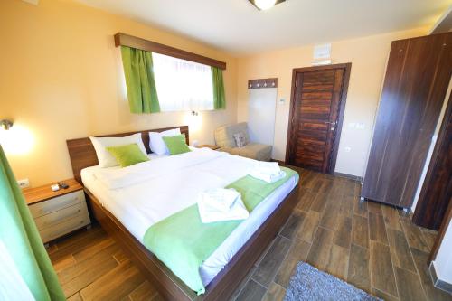 a bedroom with a large bed with green and white sheets at Vila Almax in Soko Banja