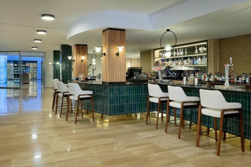 a bar with white bar stools in a restaurant at Grand Palladium Select Palace Ibiza - All Inclusive in Playa d'en Bossa
