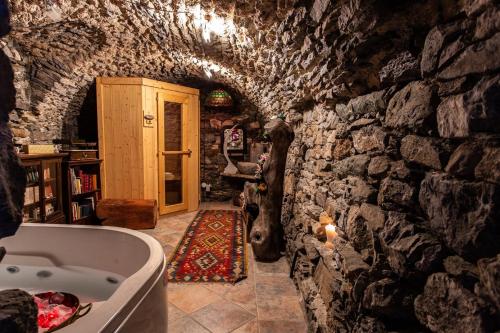 y baño con bañera y pared de piedra. en Castello di Darany,dimore con spa private con Jacuzzi e saune, en Villeneuve