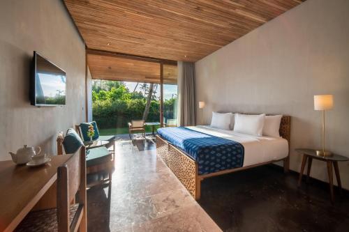 a bedroom with a bed and a desk and a television at MASMARA Resort Canggu in Canggu