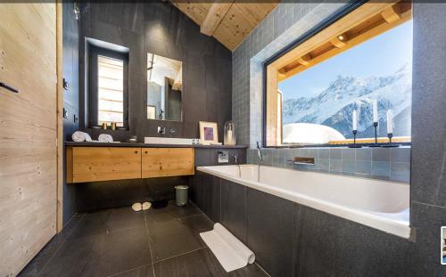 baño con bañera, lavabo y ventana en Le Chalet Mont Blanc en Les Houches