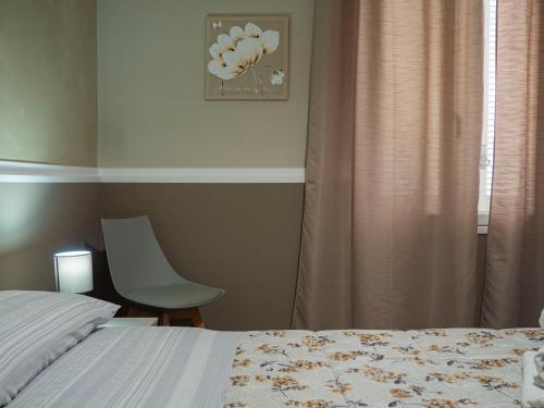 a bedroom with a bed and a chair and a window at Villa Paestum in Paestum
