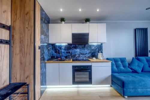 a kitchen with white cabinets and a blue couch at Apartament Panorama in Gdynia