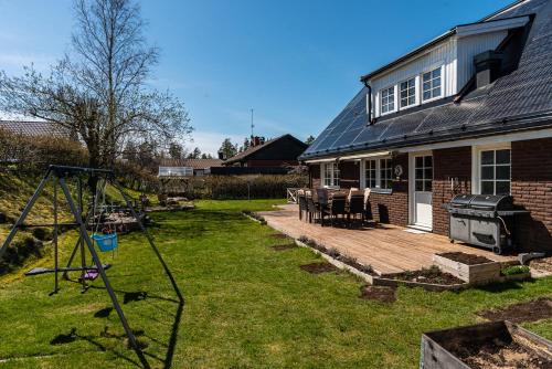 a backyard with a wooden deck and a house at Nice Villa near Lake! Free boat, sauna and big garden! in Åryd