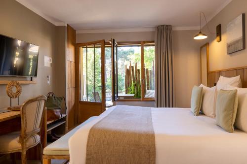 a bedroom with a bed and a desk and a window at Domaine du Ferret Restaurant & Spa in Cap-Ferret