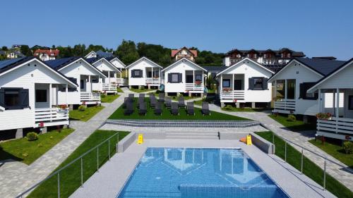 a row of white cottages with a swimming pool at Domki M&L in Polańczyk