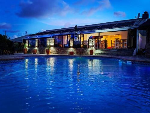 a swimming pool in front of a house at night at Aviators Paradise Guest House in Mossel Bay