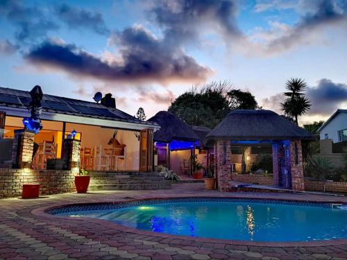 a swimming pool in front of a house at night at Aviators Paradise Guest House in Mossel Bay