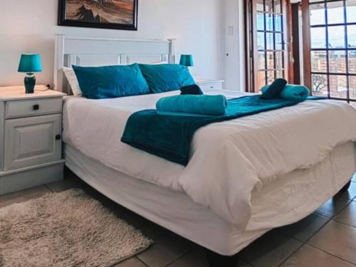 a bedroom with a large bed with blue pillows at Aviators Paradise Guest House in Mossel Bay