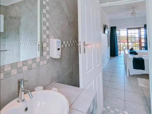 a white bathroom with a sink and a hallway at Aviators Paradise Guest House in Mossel Bay