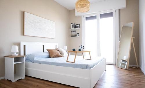a bedroom with a white bed and a table at Appartamento Nautilus in Lido di Jesolo