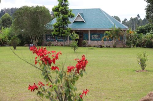 a house with red flowers in front of a yard at Muga Eco Village in Ntungamo