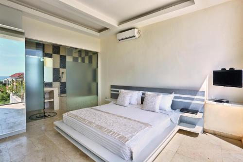 1 dormitorio con 1 cama y TV en la pared en ECHO BEACH DESIGNER APARTMENT en Canggu