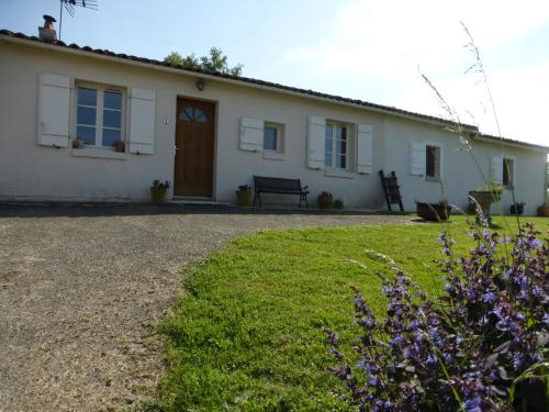 a white house with a bench and flowers in front of it at Chez Kate in Charroux