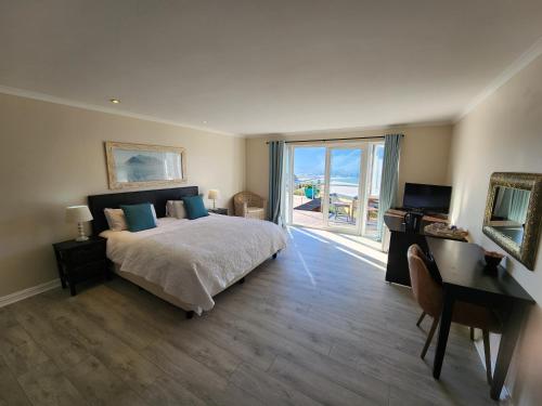 a bedroom with a bed and a desk and a window at Hout Bay Breeze Guest House in Hout Bay