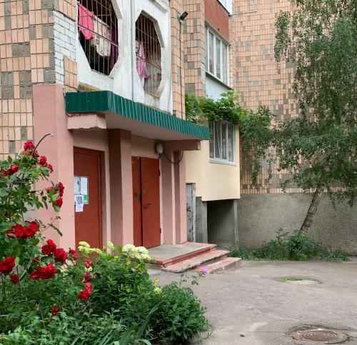 a building with a red door and some flowers at Apartaments Teris in Zhytomyr