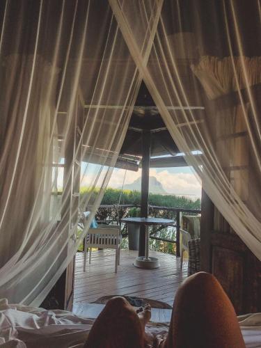 a person sitting in a bed in a room with a view at Harmonie in Rivière Noire