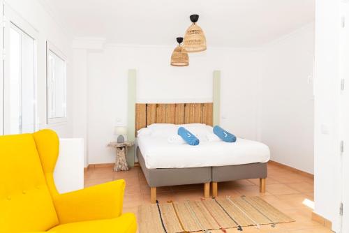a bedroom with a bed and a yellow chair at Villa Veaco Beach with jacuzzi and private pool in Corralejo
