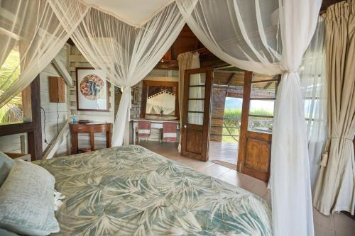 Schlafzimmer mit einem Bett mit Vorhängen und einem Schreibtisch in der Unterkunft Harmonie in Rivière Noire
