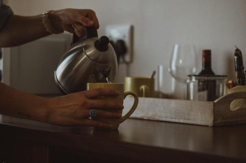 a person is holding a coffee cup on a counter at Three Olives Guesthouse in Centurion