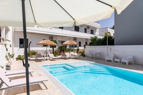 a pool with chairs and umbrellas next to a building at La Gemma del Salento Rooms&Apartments in Racale