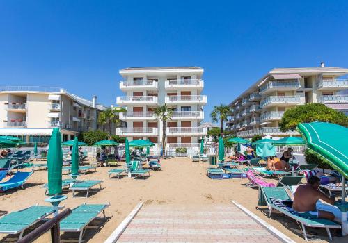 een strand met stoelen en parasols en enkele hotels bij Appartamento Nautilus in Lido di Jesolo