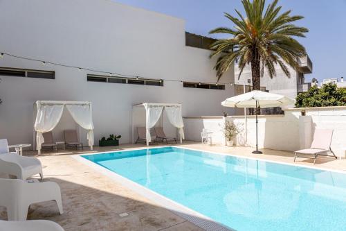 a pool with chairs and an umbrella and a palm tree at La Gemma del Salento Rooms&Apartments in Racale