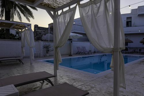 a swimming pool with white umbrellas next to a building at La Gemma del Salento Rooms&Apartments in Racale