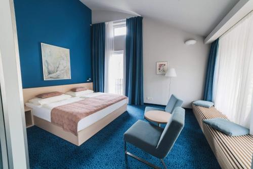 a blue bedroom with a bed and a chair at Hotel Split in Kadaň